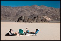 Tourists sunning themselves with beach chairs on the Racetrack. Death Valley National Park, California, USA.