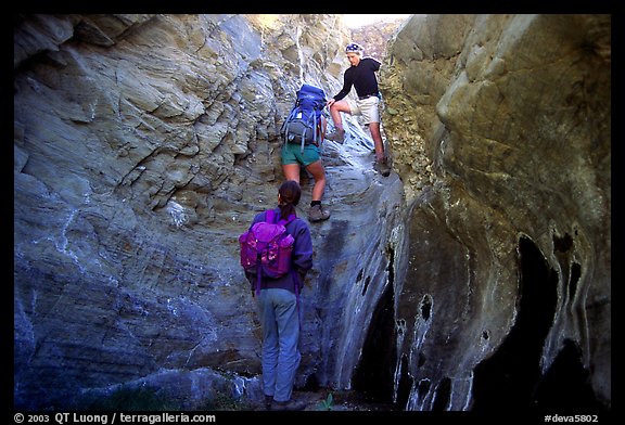 Hikers climbing in a narrow side canyon. Death Valley National Park, California, USA.