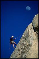 Climber rappelling down with moon. Joshua Tree National Park, California, USA.