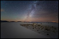 Backcountry camping area with lit tent at night. White Sands National Park, New Mexico, USA.