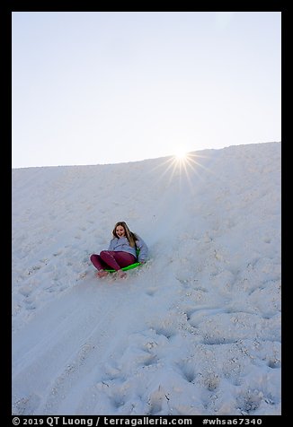 Woman sledding down dune. White Sands National Park (color)