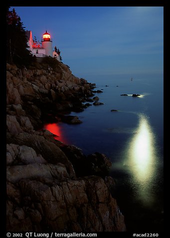 Bass Harbor lighthouse by night with reflections of moon and lighthouse light. Acadia National Park, Maine, USA.