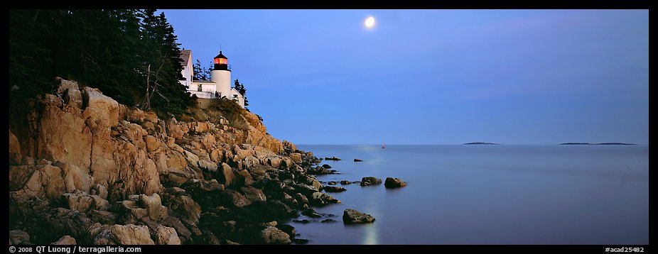 Dusk seascape with lightouse, moon, and reflection. Acadia National Park, Maine, USA.