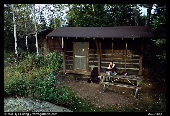 Backpacker sitting in shelter at Chippewa harbor. Isle Royale National Park, Michigan, USA.