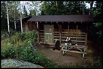 Backpacker sitting in shelter at Chippewa harbor. Isle Royale National Park, Michigan, USA.