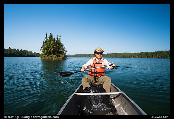 Canoist paddling and islet, Tobin Harbor. Isle Royale National Park, Michigan, USA.