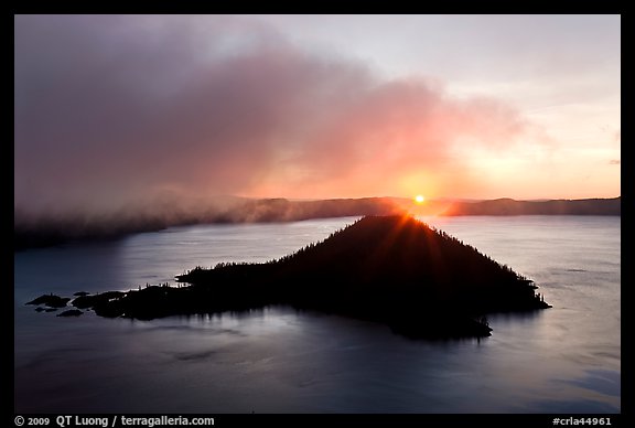 Sun rising behind Wizard Island. Crater Lake National Park, Oregon, USA.