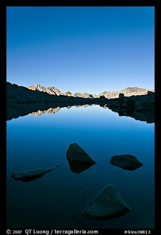 Rocks and calm lake with mountain reflections, early morning, Dusy Basin. Kings Canyon National Park, California, USA.