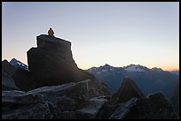 Man sitting on rock contemplates mountains at sunrise, North Cascades National Park. Washington, USA.