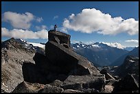 Man sitting on rock photographs mountain panorama, North Cascades National Park. Washington, USA.