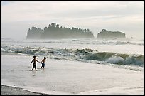 Children playing in water in front of sea stacks, Rialto Beach. Olympic National Park, Washington, USA. (color)