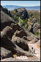 Hikers approaching cliff with steps carved in stone. Pinnacles National Park, California, USA.