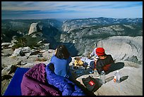 Backpackers eat breakfast, looking at Yosemite Valley from Clouds Rest. Yosemite National Park, California, USA.