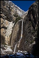 Lower Yosemite Falls and rock wall with snowy trees on rim. Yosemite National Park, California, USA.