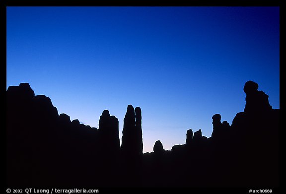 Sandstone pillars in Klondike Bluffs seen as silhouettes at dusk. Arches National Park, Utah, USA.
