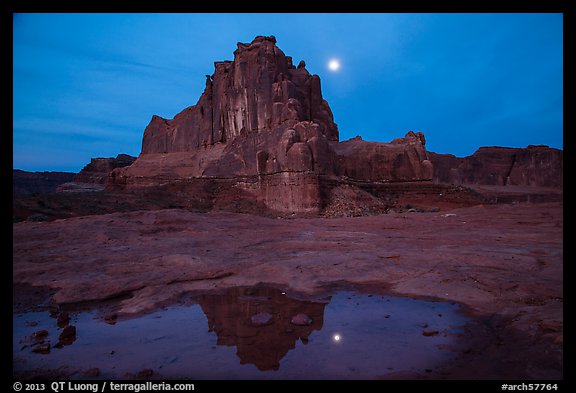 Courthouse tower and moon reflected in pothole. Arches National Park, Utah, USA.