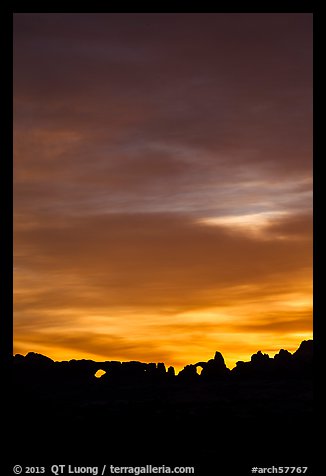 Windows and Turret Arch silhouetted against colorful clouds. Arches National Park, Utah, USA.