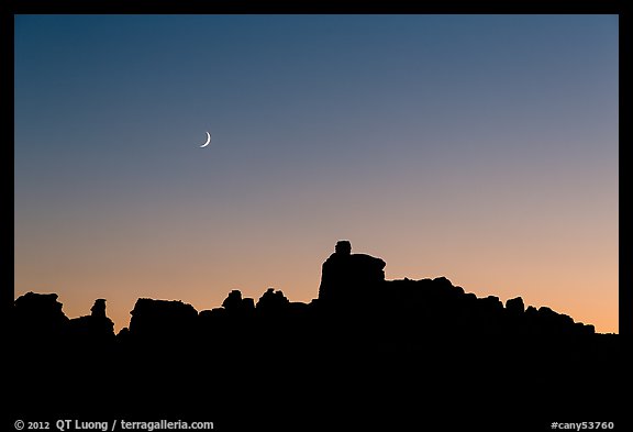 Crescent moon at sunset and Doll House spires. Canyonlands National Park, Utah, USA.