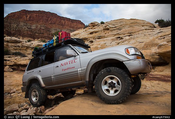 Expedition vehicle driving over rock ledge, Teapot Canyon. Canyonlands National Park, Utah, USA.