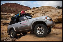 Expedition vehicle driving over rock ledge, Teapot Canyon. Canyonlands National Park, Utah, USA. (color)