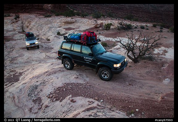 4WD vehicles driving over rock at dusk in Teapot Canyon. Canyonlands National Park (color)