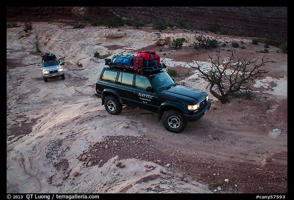 4WD vehicles driving over rock at dusk in Teapot Canyon. Canyonlands National Park (color)