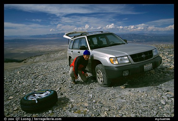 Man changing a flat tire on remote spot at top of Mt Washington. Great Basin National Park, Nevada, USA.