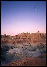 Mud cracks, badlands, and moon at dawn. Badlands National Park, South Dakota, USA.