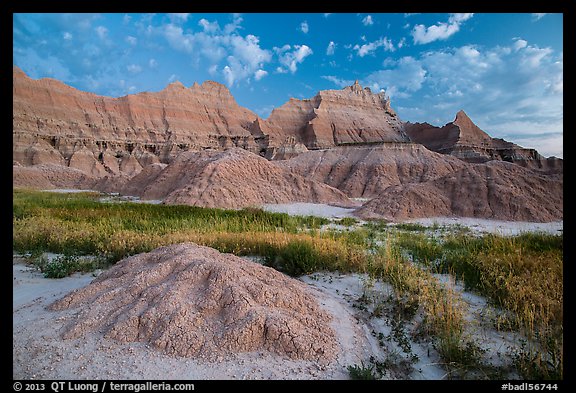 Grasses, cracked soil, and sharp peaks at dawn. Badlands National Park, South Dakota, USA.