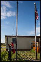 Ranger lowering Ogala Lakota flag, White River Visitor Center. Badlands National Park, South Dakota, USA. (color)