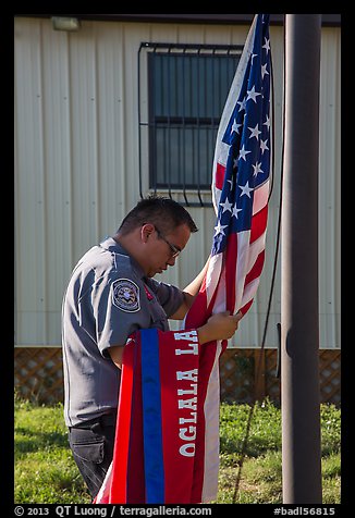 Native American ranger gathering US and Tribal flags. Badlands National Park (color)