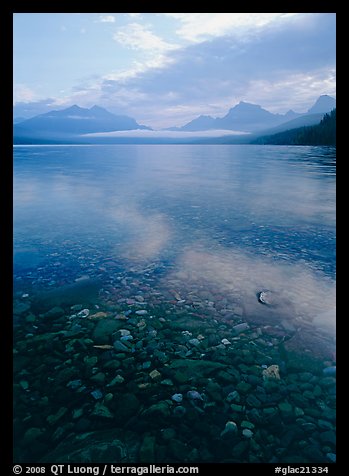 Pebbles, lake Mc Donald, and foggy mountain range, early morning. Glacier National Park, Montana, USA.