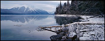 Lake, snowy shore, and mountains in winter. Glacier National Park, Montana, USA.