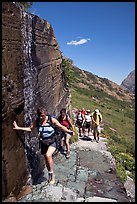 Walking under a small waterfall on the Grinnell Glacier trail. Glacier National Park, Montana, USA.