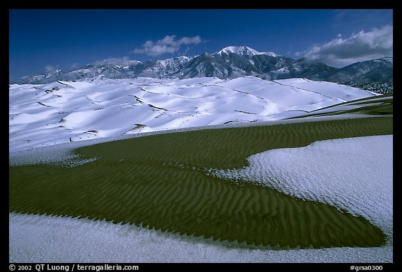 Patch of sand, snow-covered dunes, Sangre de Christo mountains. Great Sand Dunes National Park, Colorado, USA.