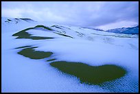 Patch of sand in snow-covered dunes. Great Sand Dunes National Park, Colorado, USA.