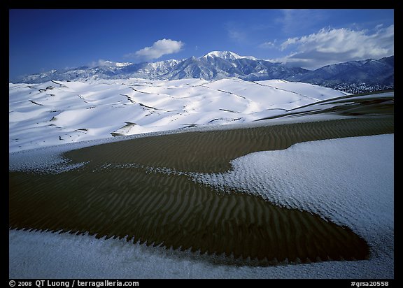 Patch of sand, snow-covered dunes, Sangre de Christo mountains. Great Sand Dunes National Park and Preserve, Colorado, USA.