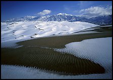 Patch of sand, snow-covered dunes, Sangre de Christo mountains. Great Sand Dunes National Park and Preserve, Colorado, USA.