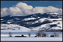 Distant row of barns, hills and clouds in winter. Grand Teton National Park, Wyoming, USA.