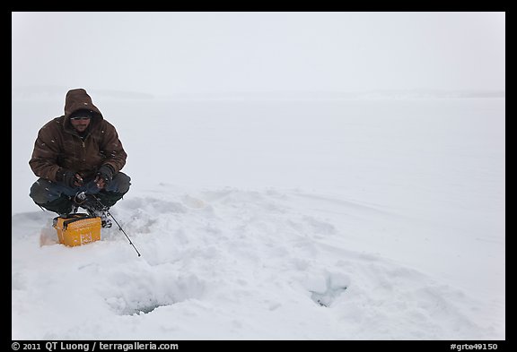 Man ice fishing on frozen Jackson Lake. Grand Teton National Park (color)