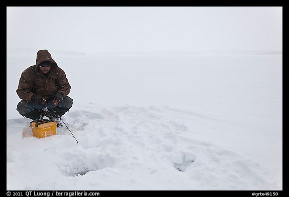 Man ice fishing on frozen Jackson Lake. Grand Teton National Park, Wyoming, USA.