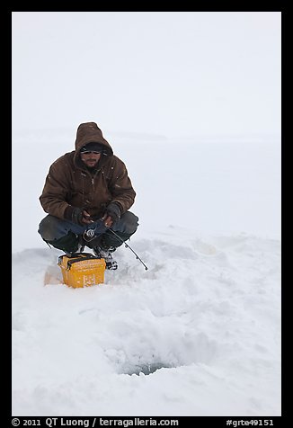 Ice fishing during a snow storm, Jackson Lake. Grand Teton National Park, Wyoming, USA.