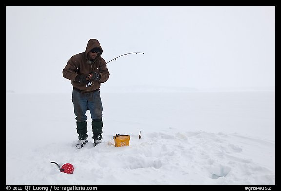Ice fisherman standing next to hole, Jackson Lake. Grand Teton National Park, Wyoming, USA.
