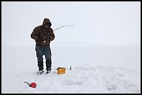 Ice fisherman standing next to hole, Jackson Lake. Grand Teton National Park, Wyoming, USA.