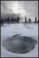 Thermal pool and dark clouds, winter. Yellowstone National Park, Wyoming, USA.