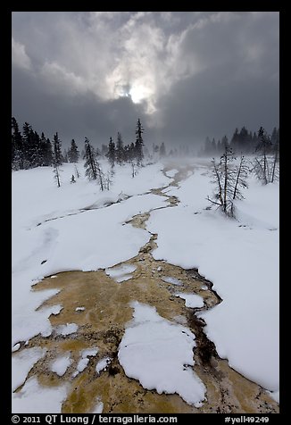 Colorful thermal stream and dark clouds, winter. Yellowstone National Park, Wyoming, USA.