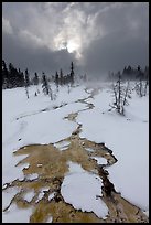 Colorful thermal stream and dark clouds, winter. Yellowstone National Park, Wyoming, USA.