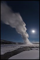 Night view of Old Faithful Geyser in winter with full moon. Yellowstone National Park, Wyoming, USA.