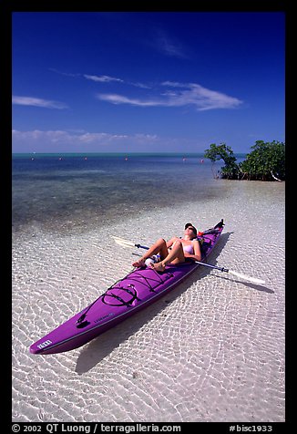 Woman sunning herself on sea kayak parked on shore,  Elliott Key. Biscayne National Park, Florida, USA.