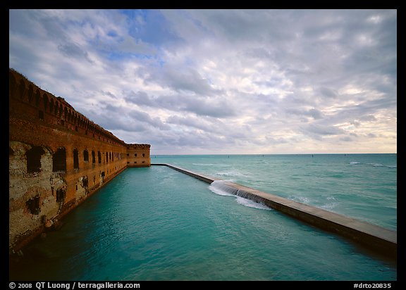 Fort Jefferson brick rampart and moat with wave over seawall, cloudy weather. Dry Tortugas National Park, Florida, USA.